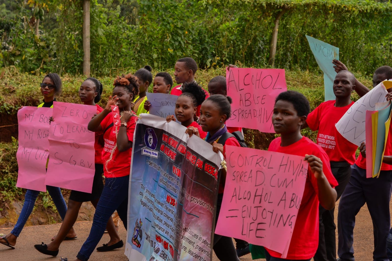 Young people in red T-shirts marching with hand-written placards