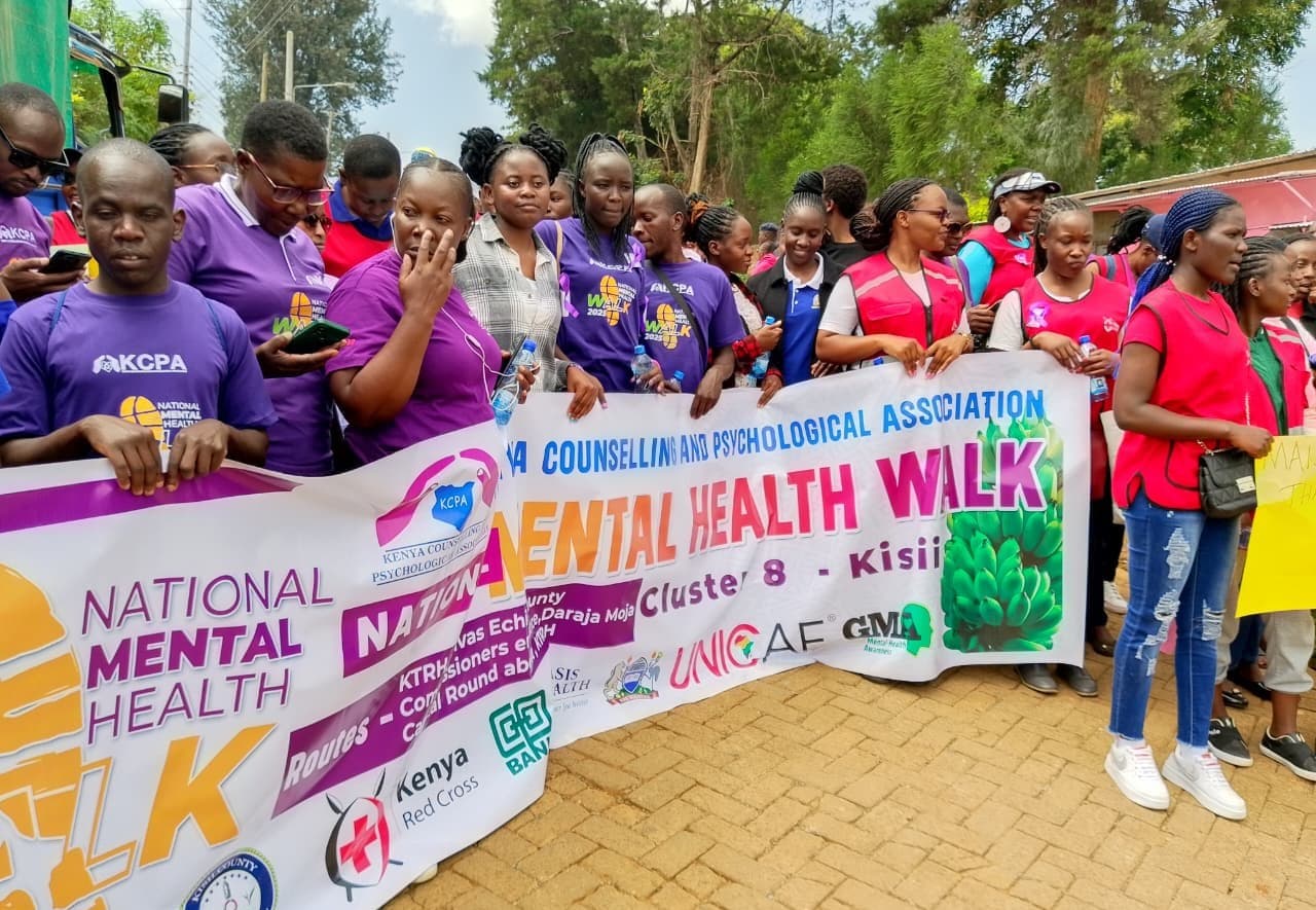 Young people holding a National Mental Health Walk banner on a street in Kisii