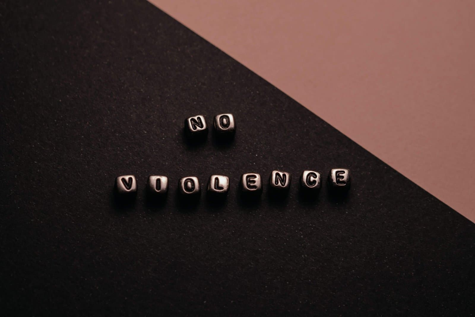 Letter beads spelling NO VIOLENCE on a dark background