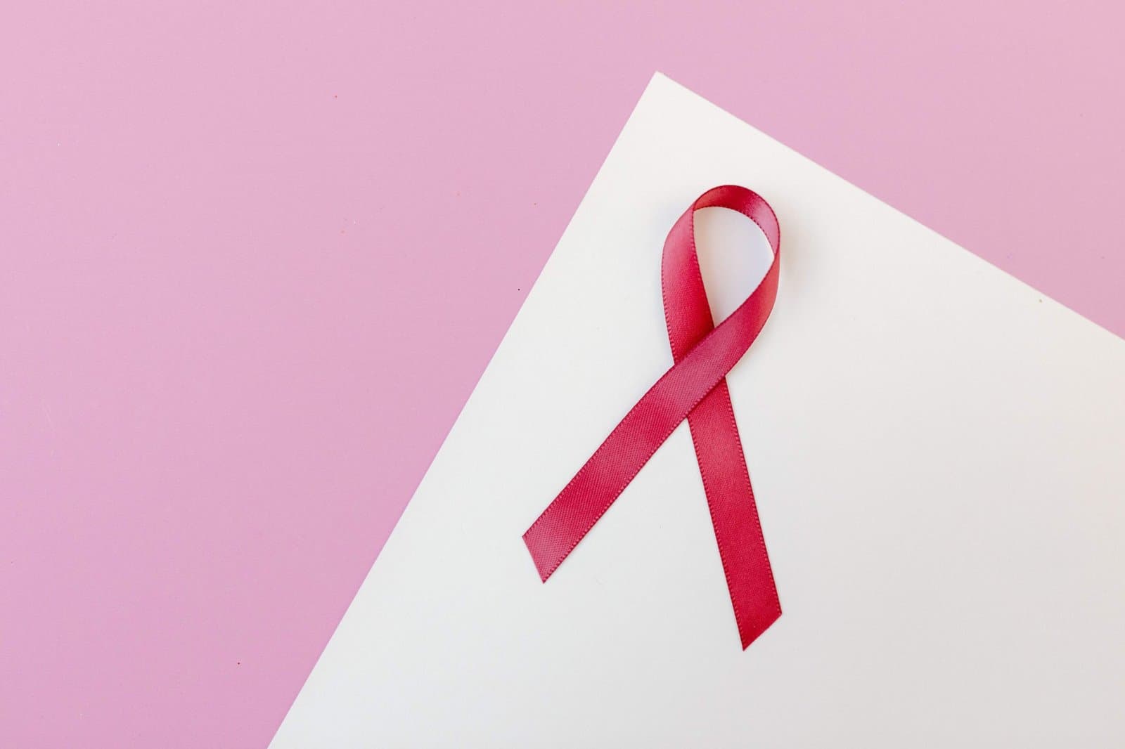 A red awareness ribbon on white and pink paper